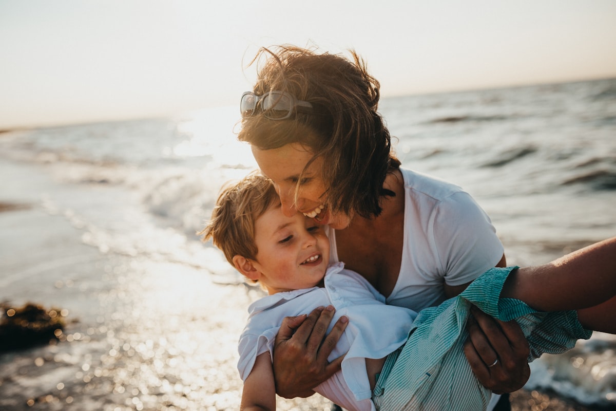 A parent holding their young child at the beach